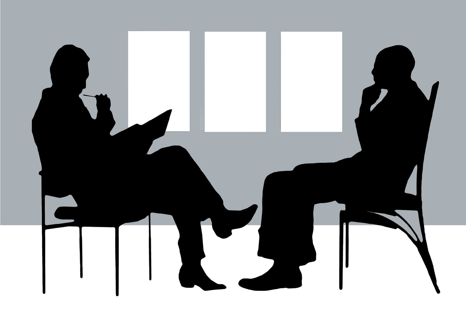 A silhouette of two people talking. One speaks while the other takes notes